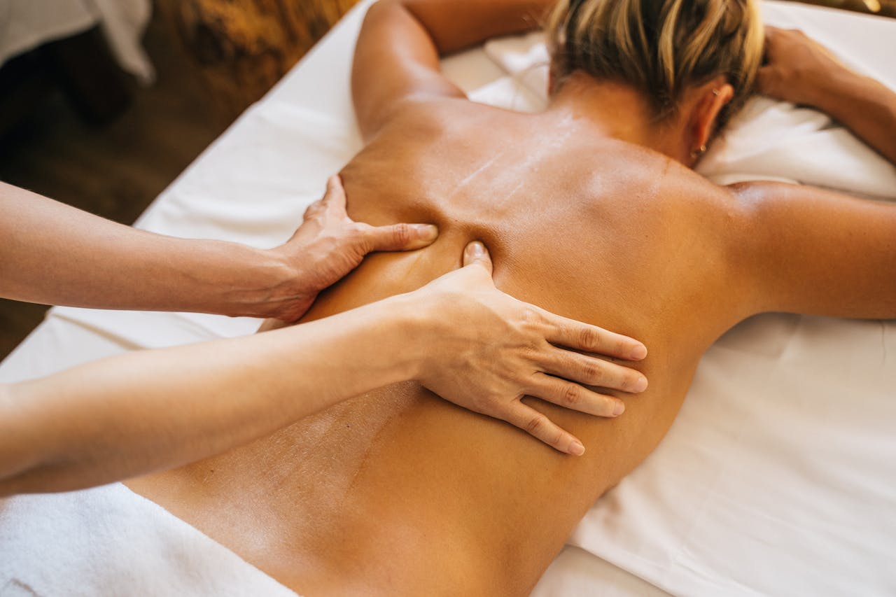 A Person Massaging a Client's Bare Back